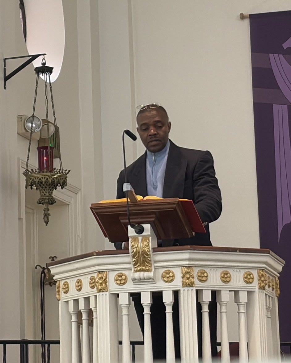 Docteur Kerold reading from the lectern at church